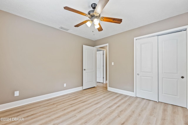 unfurnished bedroom featuring ceiling fan, a textured ceiling, a closet, and light wood-type flooring