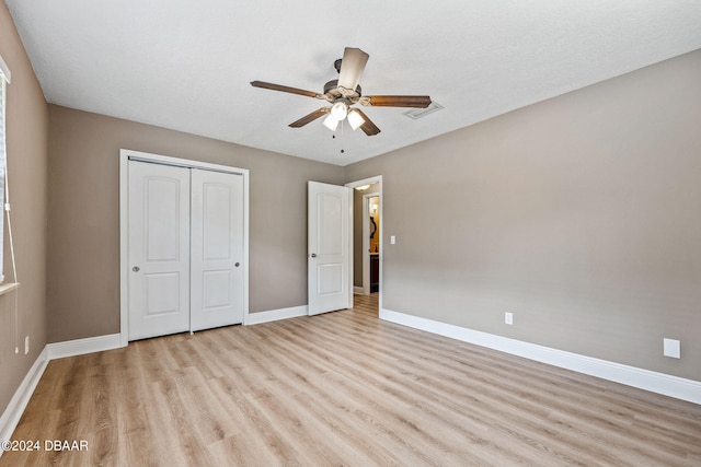 unfurnished bedroom with ceiling fan, a textured ceiling, a closet, and light wood-type flooring