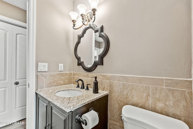 bathroom featuring toilet, vanity, and tile walls