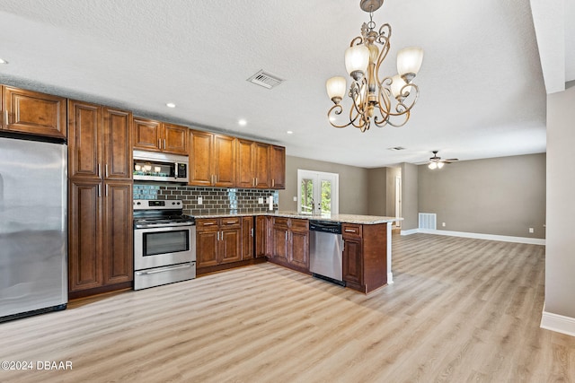 kitchen with ceiling fan with notable chandelier, stainless steel appliances, light hardwood / wood-style floors, kitchen peninsula, and hanging light fixtures