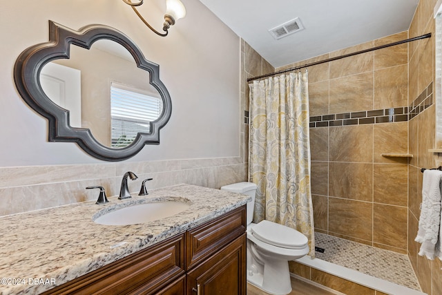 bathroom with tile walls, walk in shower, toilet, and vanity