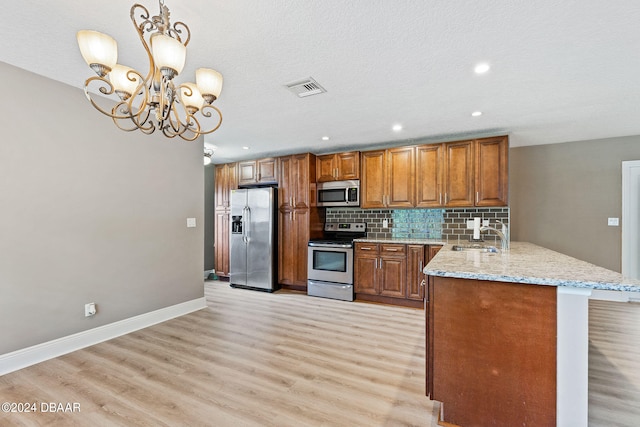 kitchen featuring kitchen peninsula, light hardwood / wood-style floors, decorative light fixtures, and appliances with stainless steel finishes