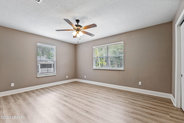 empty room with light wood-type flooring, a wealth of natural light, a textured ceiling, and ceiling fan