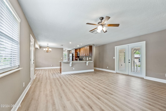 unfurnished living room with light hardwood / wood-style flooring, sink, a textured ceiling, and plenty of natural light