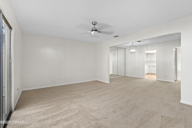 carpeted empty room with ceiling fan with notable chandelier