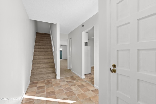 stairway featuring a textured ceiling