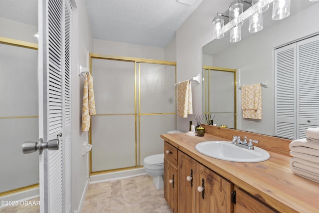 bathroom with a shower with door, vanity, a textured ceiling, and toilet