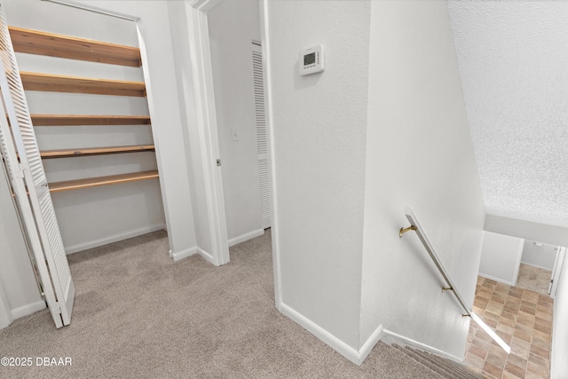 hallway with light colored carpet and a textured ceiling