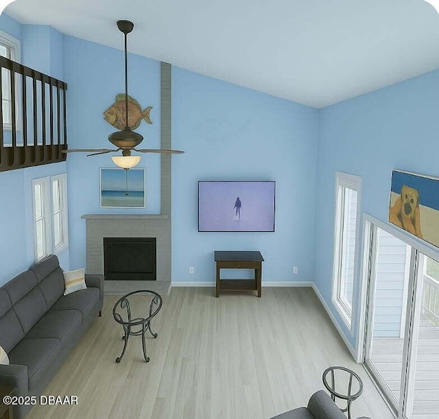 living area featuring baseboards, a ceiling fan, wood finished floors, and a brick fireplace