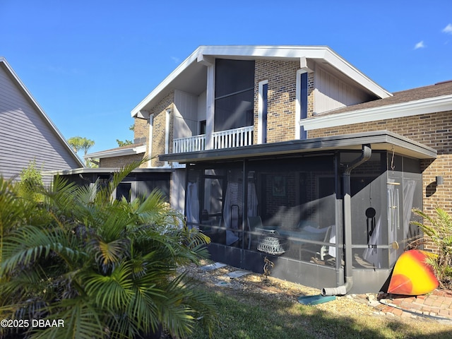 113 Lagoon Ct, New Smyrna Beach, FL 32169 - back of house with brick siding, a sunroom, and a balcony