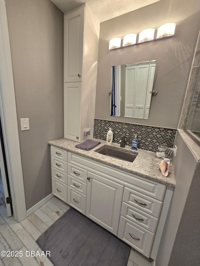 bathroom with vanity, hardwood / wood-style floors, tasteful backsplash, and a textured ceiling