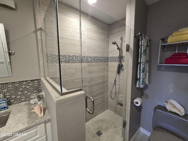 bathroom featuring vanity, decorative backsplash, a shower with shower door, and toilet