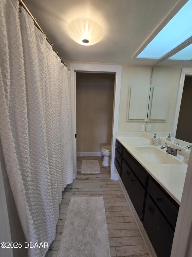 bathroom with vanity, toilet, a skylight, and hardwood / wood-style floors