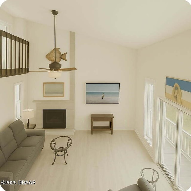 living area with a fireplace with raised hearth, baseboards, ceiling fan, and wood finished floors