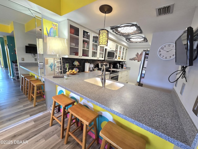 kitchen with white cabinetry, stainless steel appliances, kitchen peninsula, and a kitchen bar