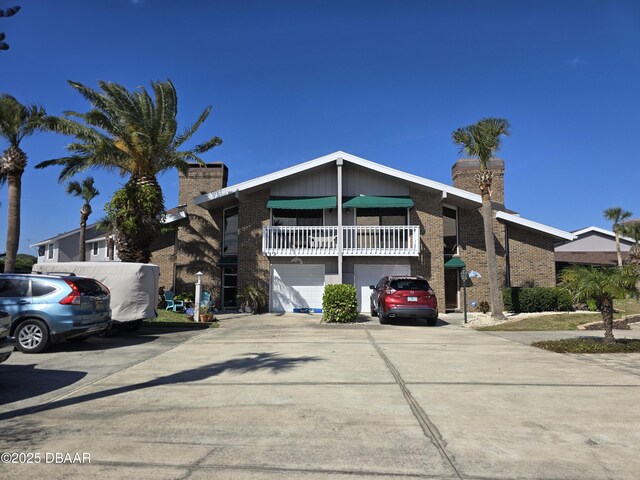 113 Lagoon Ct, New Smyrna Beach, FL 32169 - view of front of property with an attached garage, a chimney, driveway, and brick siding