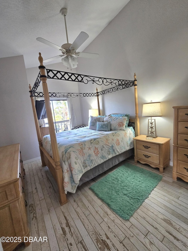 bedroom with ceiling fan, lofted ceiling, light hardwood / wood-style floors, and a textured ceiling