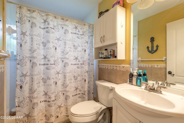 full bathroom featuring vanity, a shower with curtain, wainscoting, tile walls, and toilet