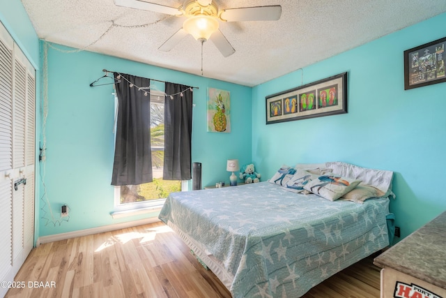 bedroom with baseboards, wood finished floors, a closet, a textured ceiling, and a ceiling fan