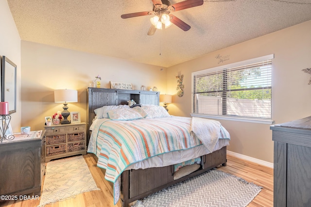 bedroom featuring ceiling fan, a textured ceiling, baseboards, and wood finished floors