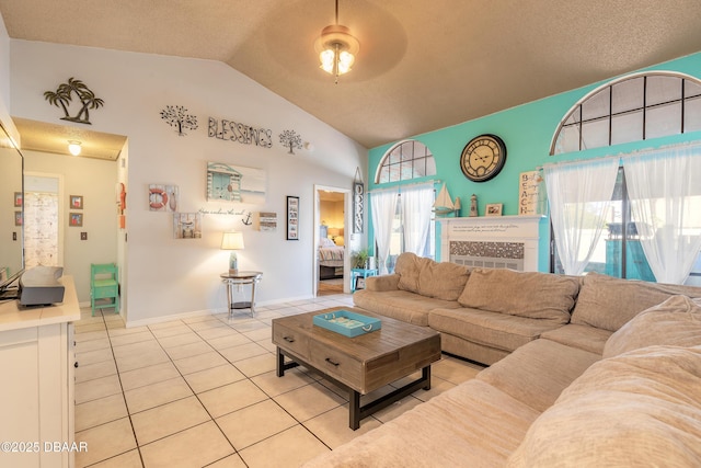 living area featuring tile patterned floors, a textured ceiling, baseboards, ceiling fan, and vaulted ceiling