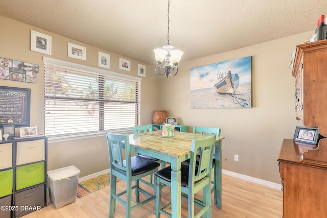 dining area featuring an inviting chandelier, baseboards, light wood finished floors, and a textured ceiling