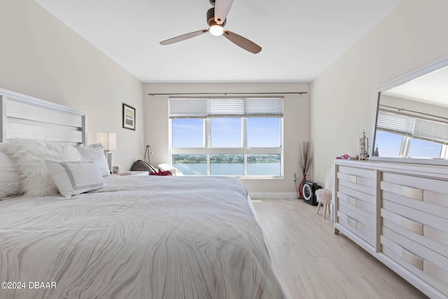 bedroom featuring ceiling fan, a water view, and light hardwood / wood-style flooring