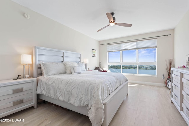 bedroom with ceiling fan, a water view, and light hardwood / wood-style floors