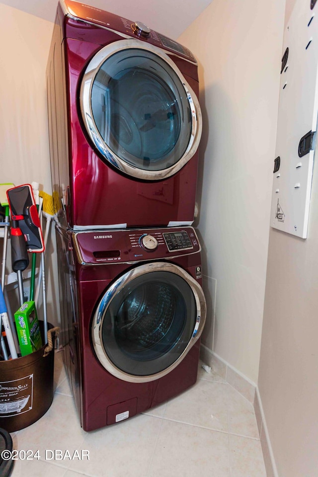 clothes washing area featuring light tile patterned flooring and stacked washer and clothes dryer