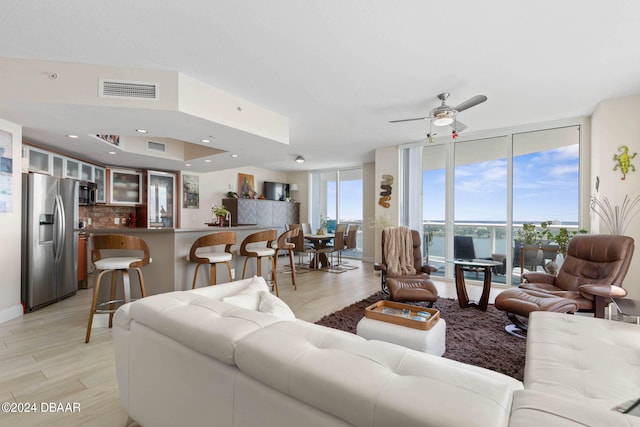 living room featuring ceiling fan, a water view, a healthy amount of sunlight, and light hardwood / wood-style flooring