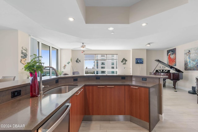 kitchen with a raised ceiling, sink, light hardwood / wood-style floors, dishwasher, and ceiling fan