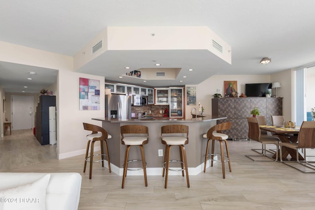 kitchen with kitchen peninsula, sink, tasteful backsplash, a kitchen breakfast bar, and appliances with stainless steel finishes