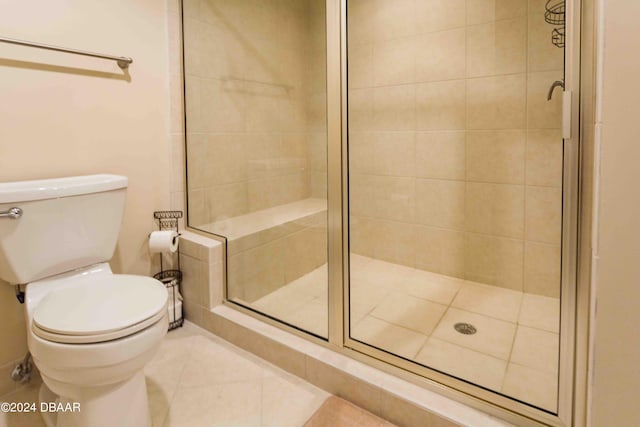 bathroom featuring a shower with door, tile patterned flooring, and toilet