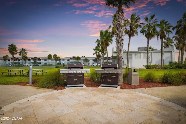 patio terrace at dusk with area for grilling and a yard