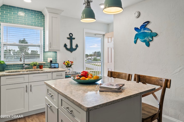 kitchen with white cabinetry, sink, a breakfast bar, and a center island