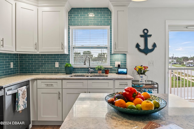 kitchen featuring backsplash, light stone countertops, sink, white cabinets, and dishwasher