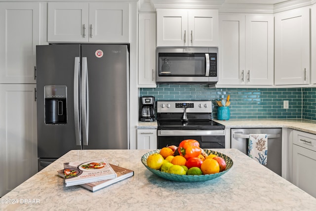 kitchen with white cabinetry, appliances with stainless steel finishes, backsplash, and light stone countertops