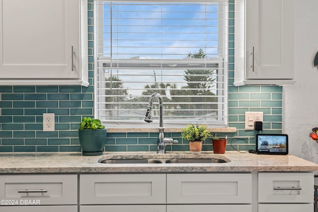 kitchen with white cabinets, decorative backsplash, sink, and light stone counters