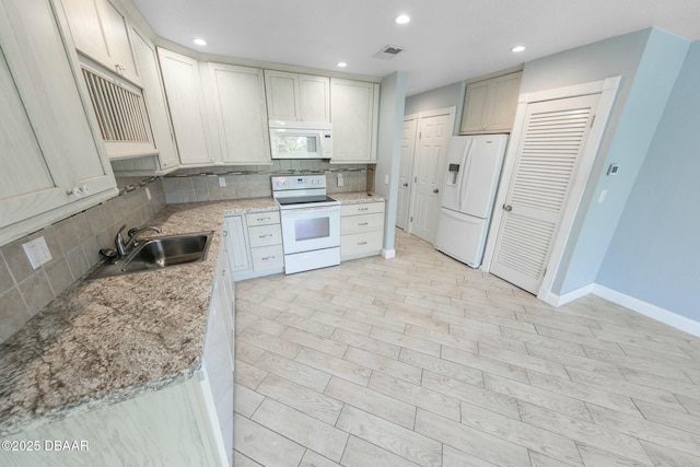 kitchen featuring tasteful backsplash, white appliances, light stone countertops, and sink