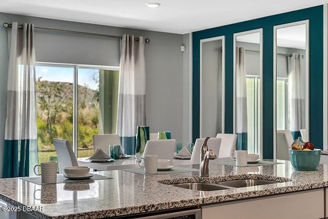 interior space with light stone counters, sink, and dishwasher