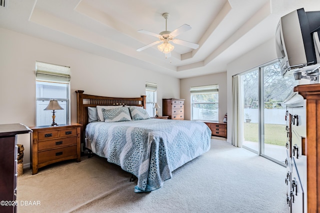 carpeted bedroom with a raised ceiling, access to outside, and ceiling fan