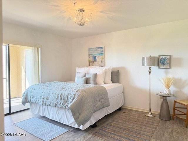 460 Bouchelle Dr Unit 104, New Smyrna Beach, FL 32169 - bedroom featuring access to outside, baseboards, an inviting chandelier, and wood finished floors