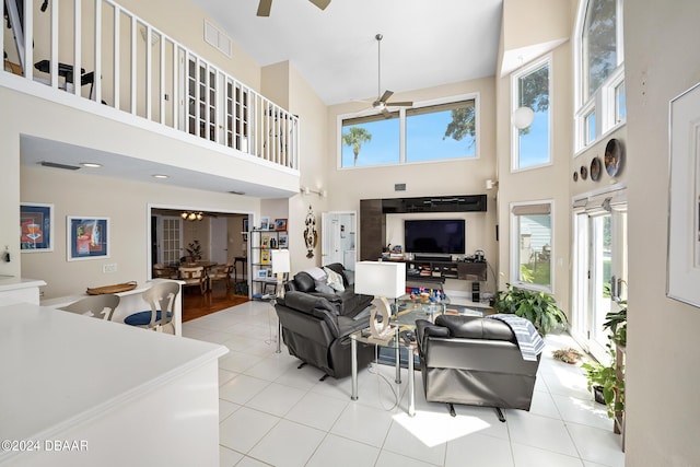 living room featuring ceiling fan, light tile patterned floors, and a high ceiling