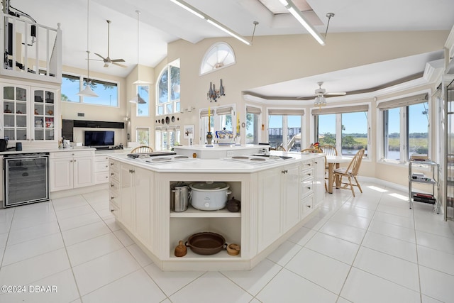 kitchen with a kitchen island with sink, white stovetop, hanging light fixtures, wine cooler, and light tile patterned flooring