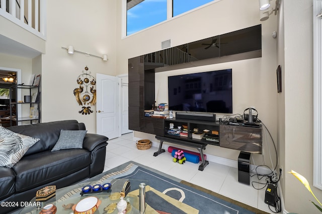 tiled living room with ceiling fan and a towering ceiling