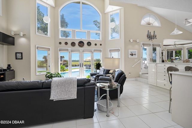 living room with light tile patterned flooring, french doors, ceiling fan, and a high ceiling