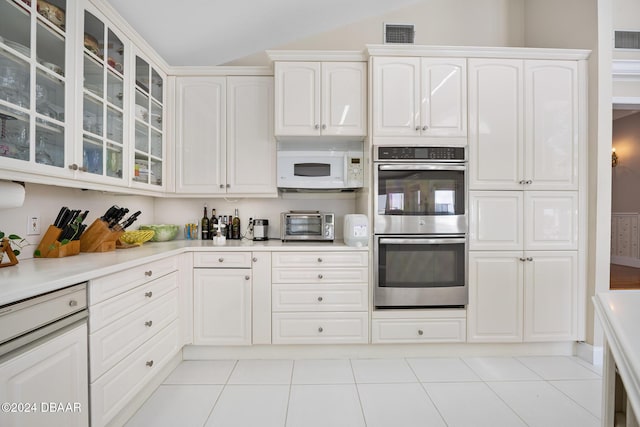 kitchen with light tile patterned floors, white cabinetry, and double oven