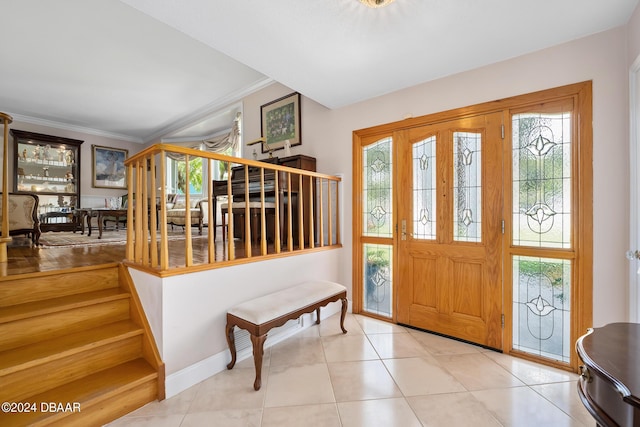 foyer with light tile patterned floors and crown molding