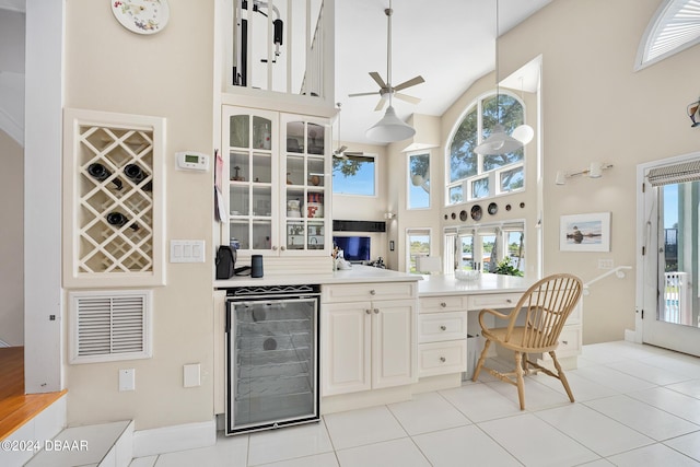 kitchen with a high ceiling, light tile patterned floors, beverage cooler, and ceiling fan