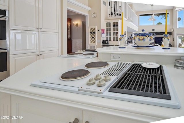 kitchen featuring decorative light fixtures, white cabinetry, and white stovetop